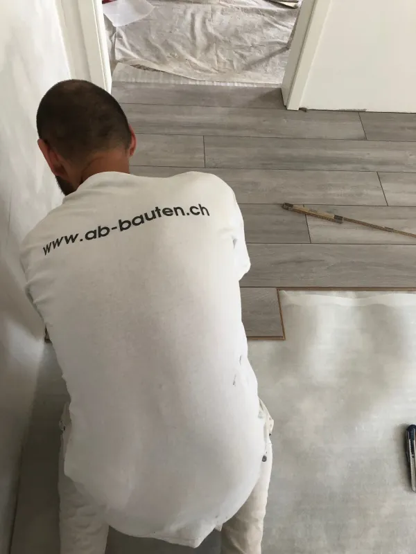 Mitarbeiter der AB Bauten AG beim Verlegen des Bodenbelags